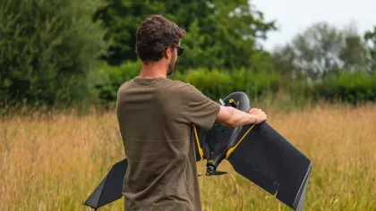 A scientist holds a fixed wing drone