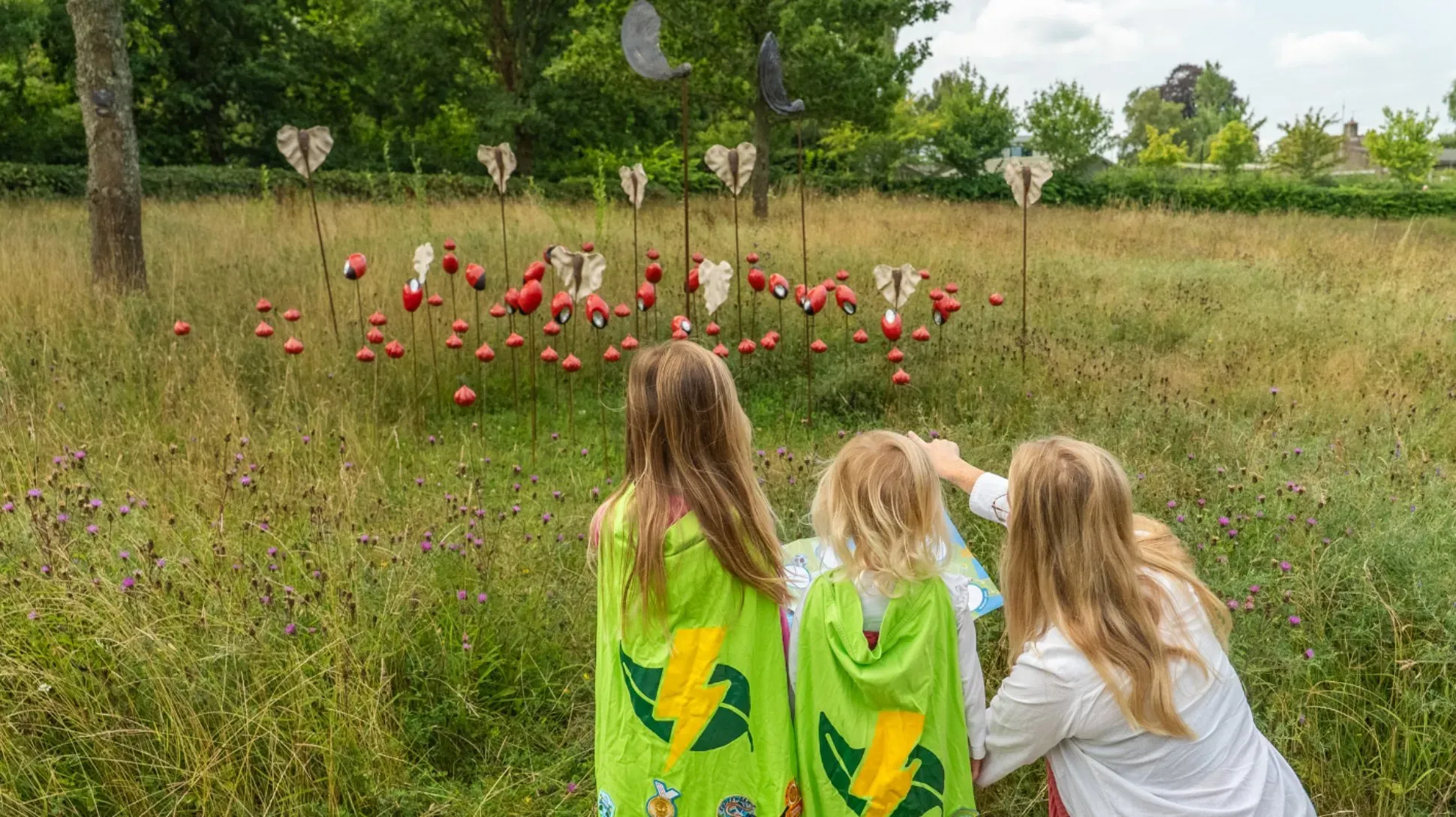 A family look at ceramic seed sculptures by Adam Ceramic in a wildflower meadow
