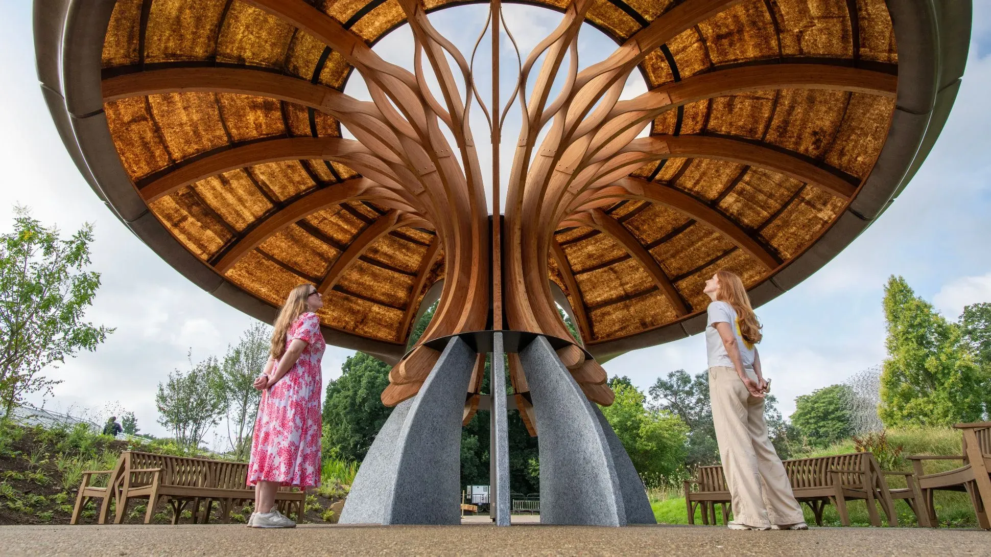 A large mushroom like structure in the Carbon Garden at Kew Gardens with two people looking up at it