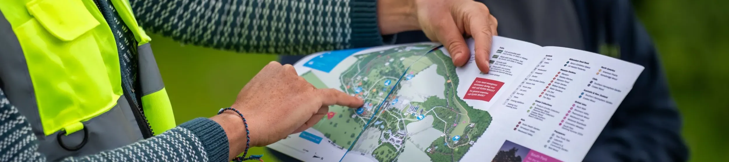 A person in a vibrant hi vis jacket pointing at a map