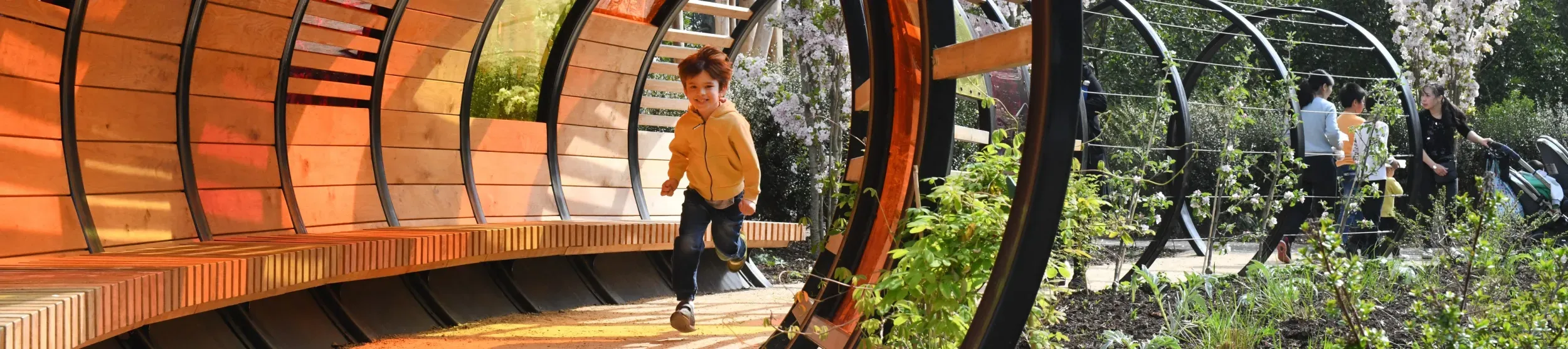 Young boy running through a wooden tunnel in the sun