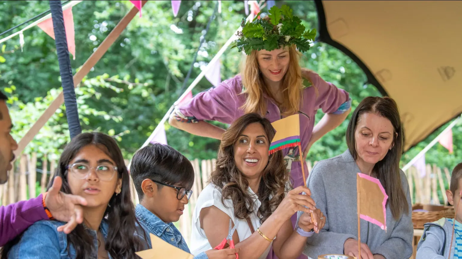 A person in a purple jump suit overseeing a crafting activity for families