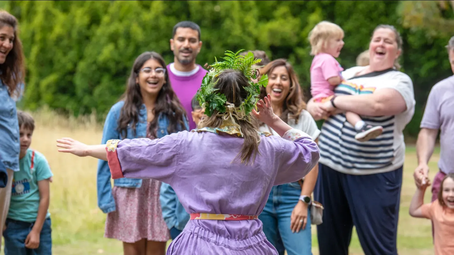 A person in a purple jump suit performing to a group of children and adults