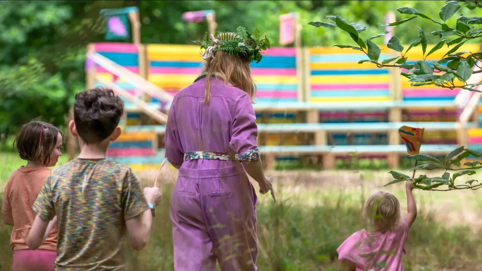 People walking through a forest towards a colourful amphitheatre
