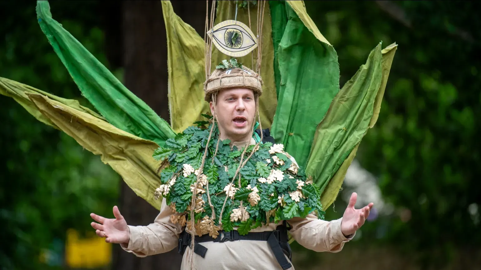 A person wearing an outfit made of oak leaves and branches performing