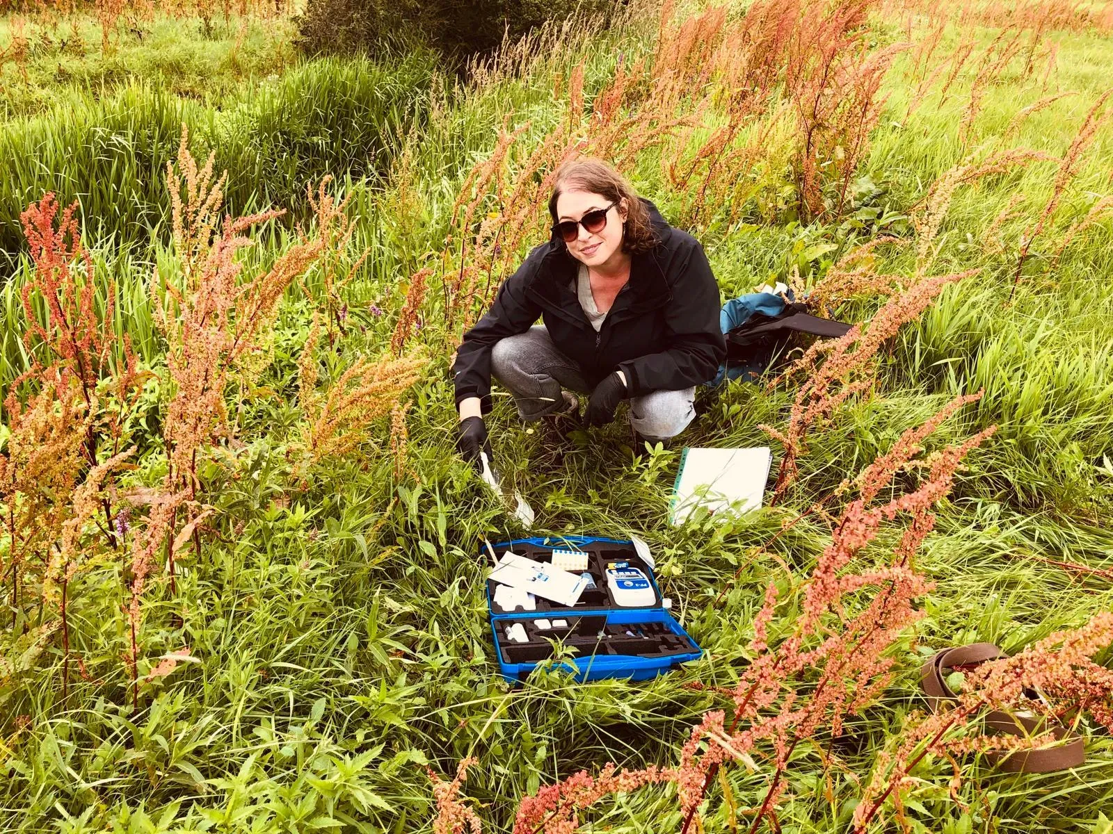 Tara Dawson, workshop leader, in a green field with equipment in front of her